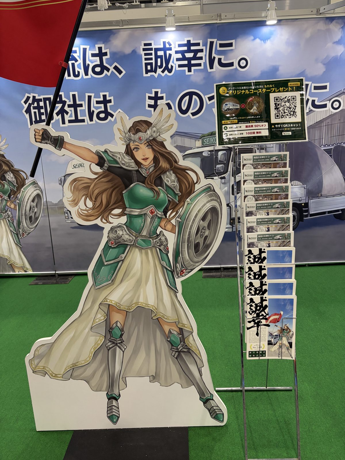 旗を持つセイコの等身大パネルと、マンガの冊子を並べたラック